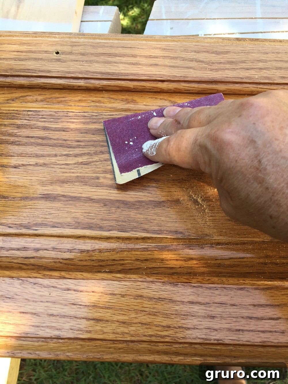 Close-up of sanding cabinets to prepare for painting, emphasizing grain direction.