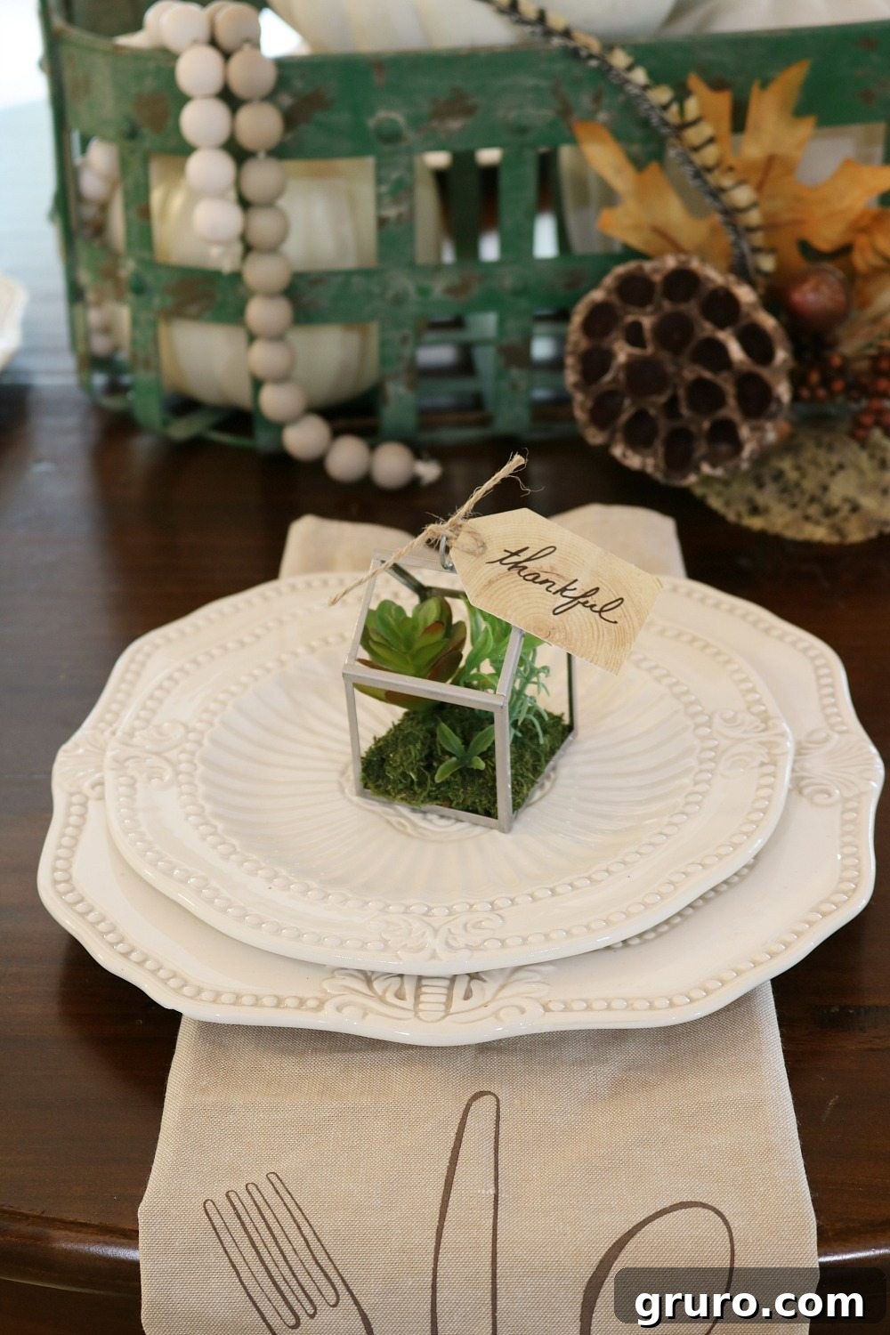 A tiny green house filled with succulents, part of a unique fall table centerpiece.