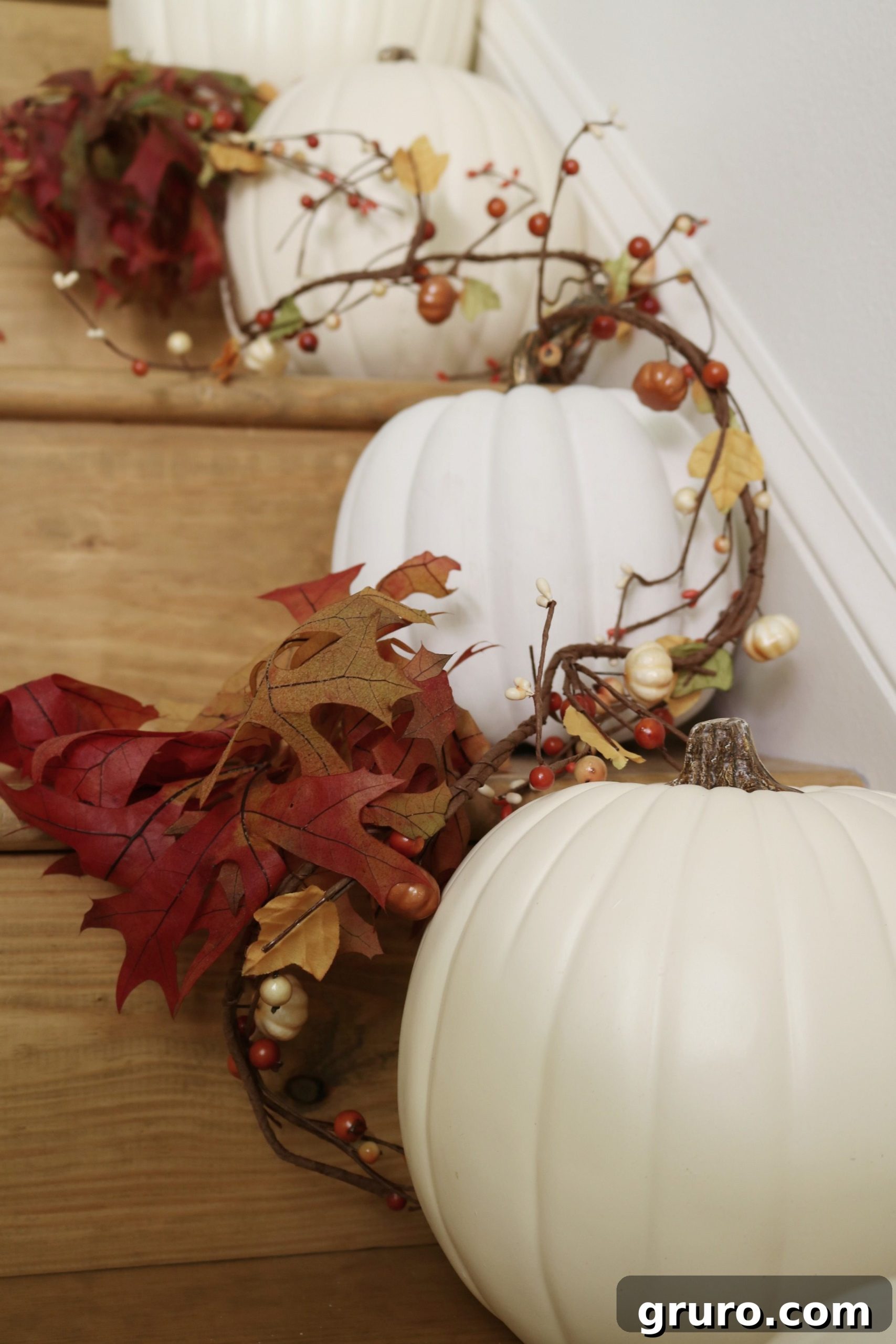Staircase lined with faux white pumpkins, creating an elegant fall entry statement.