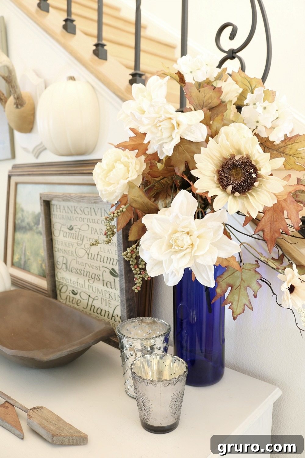 Cream flowers in a blue vase, a handmade dough bowl, and natural elements for fall decor.