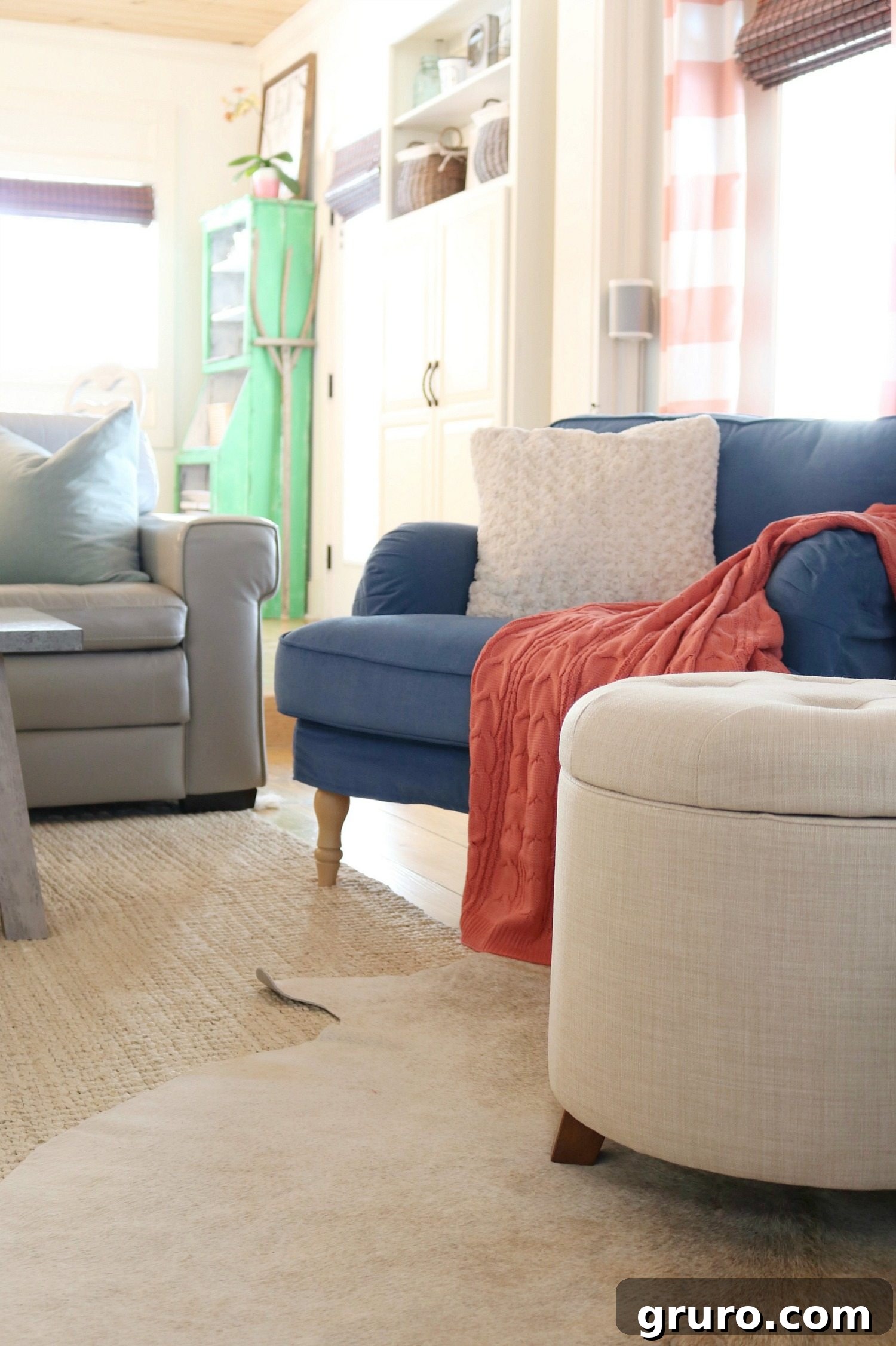 The BH&G Colette Tufted Storage Ottoman, a beloved piece from Better Homes & Gardens at Walmart, anchors a living room featuring a gallery wall with a television, a painted fireplace, and abundant color in an eclectic farmhouse style. Sponsored content.