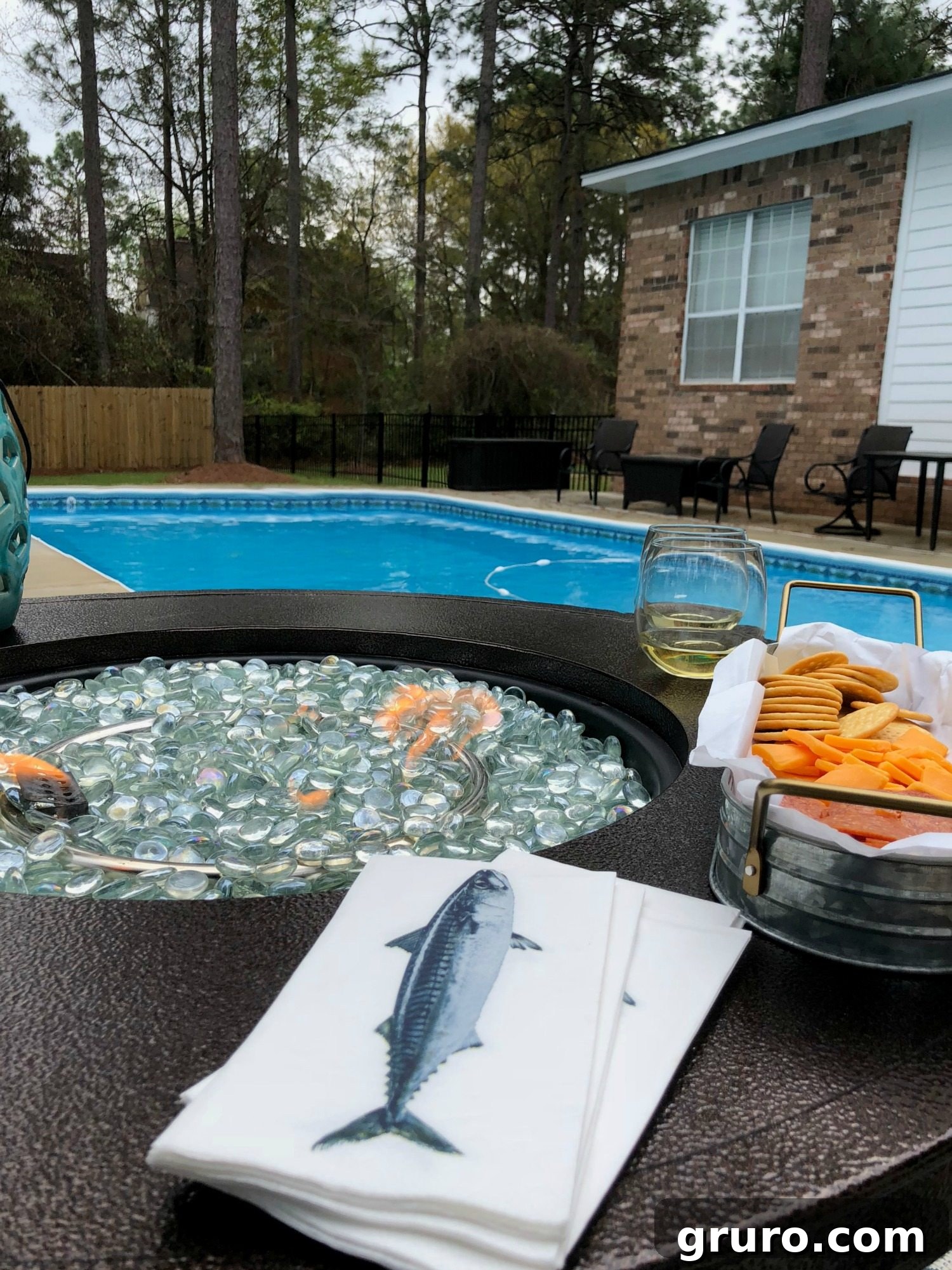 A serene evening view by the pool, illuminated by the warm glow of a fire pit, creating an inviting outdoor ambiance.