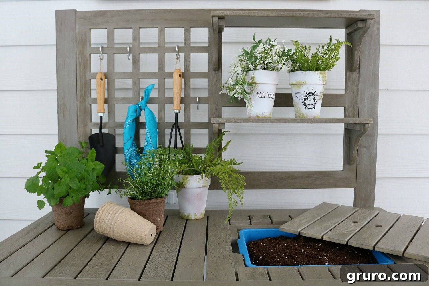A charming walnut canvas poster hung above the white Camrose Potting Bench on a back porch.