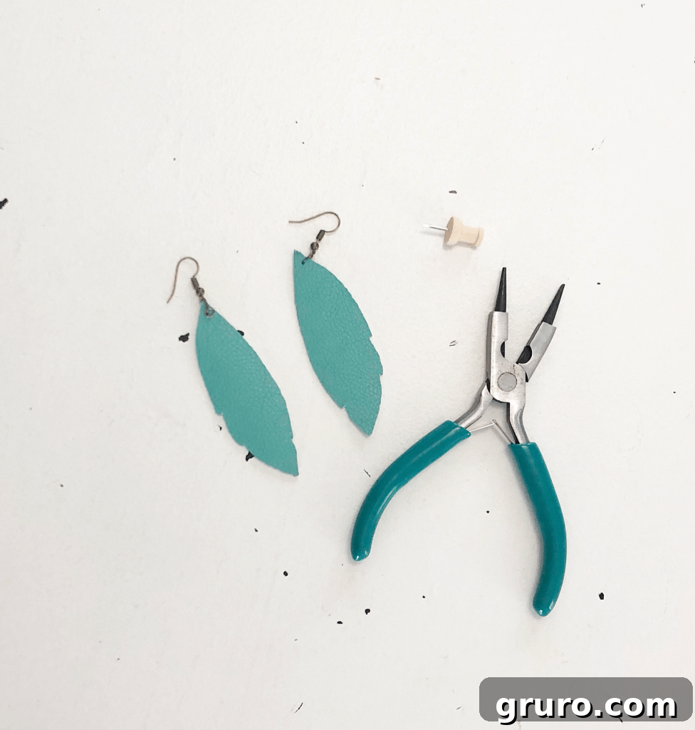 Assembling Your DIY Leather Feather Earrings – Follow This Easy Cricut Tutorial Jewelry pliers and pin used for assembling DIY leather earrings made with Cricut.