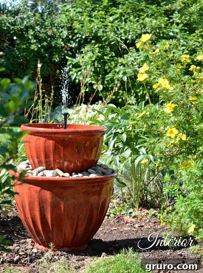 An elegant multi-tiered solar plant pot fountain, combining greenery with flowing water for a serene garden ambiance.