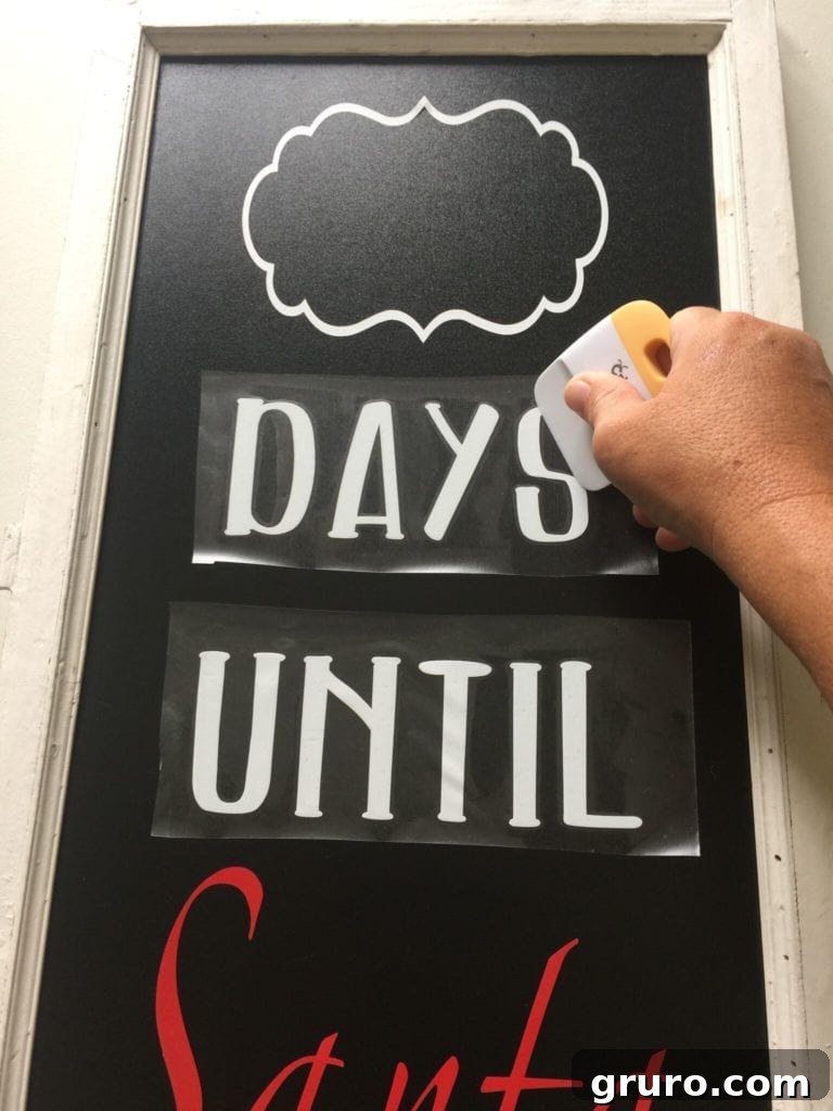 Detailed shot of vinyl being applied to a Santa sign chalkboard.