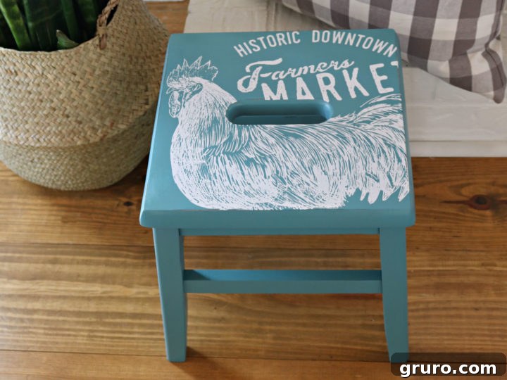 Close-up of a freshly painted wooden step stool, showcasing the smooth vintage teal finish and delicate stencil work.