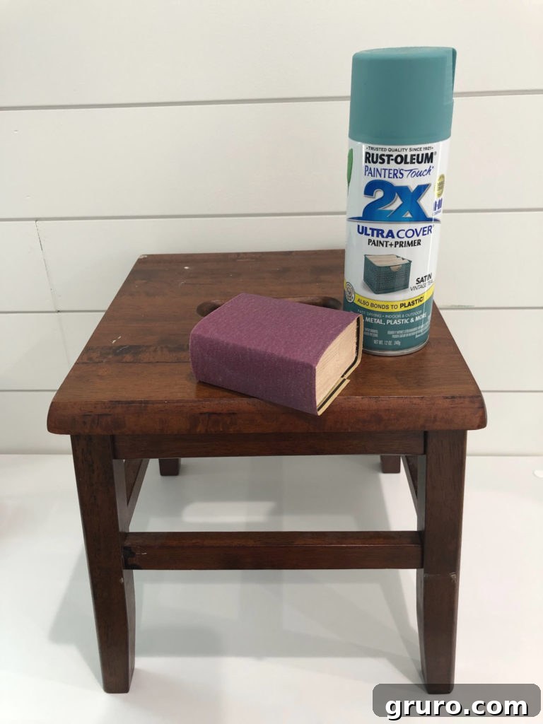 Wooden Step Stool Reimagined 6 Hands carefully sanding a wooden step stool with a sanding block to prepare it for painting, highlighting the importance of surface prep.