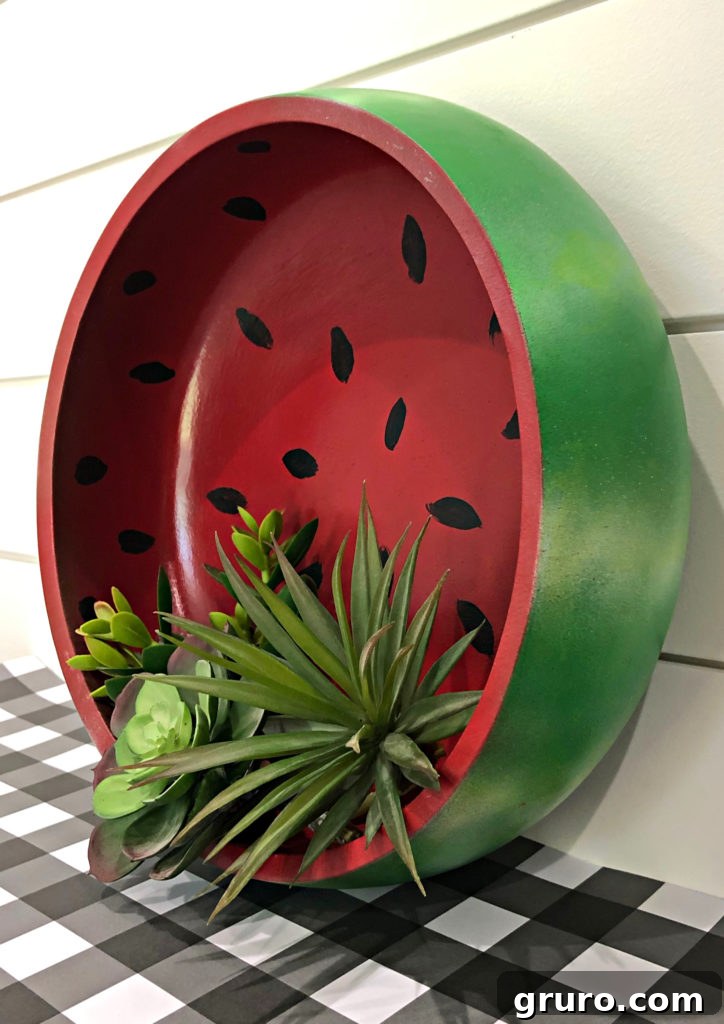Watermelon themed wooden bowl on display with greenery