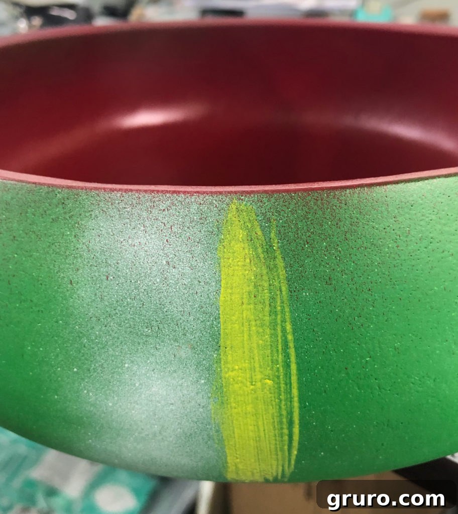 Applying yellow craft paint next to white stripes on watermelon bowl