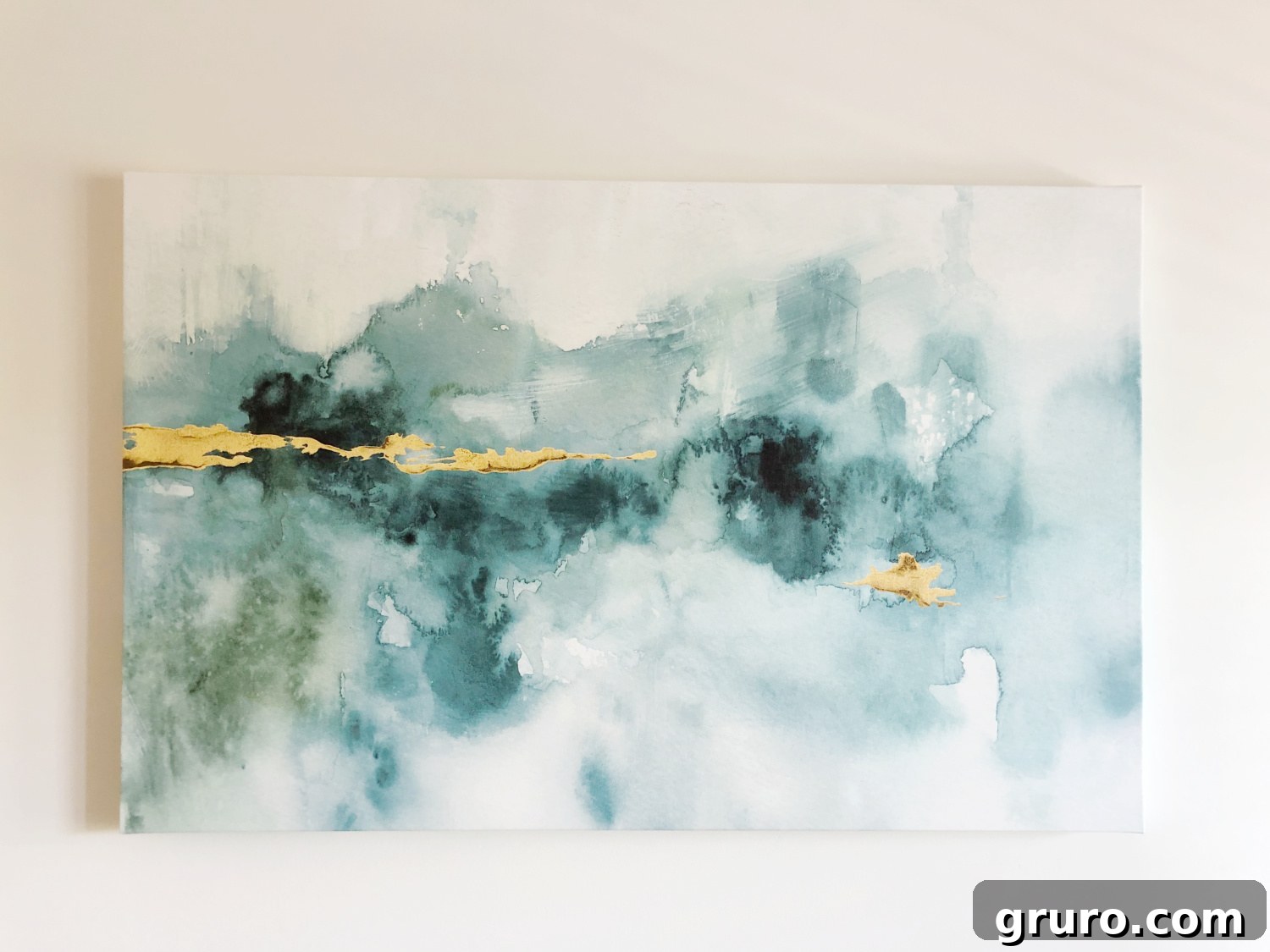 Abstract art in teal and gold tones, setting the sophisticated theme for a stylish lake condo or beach house living room.