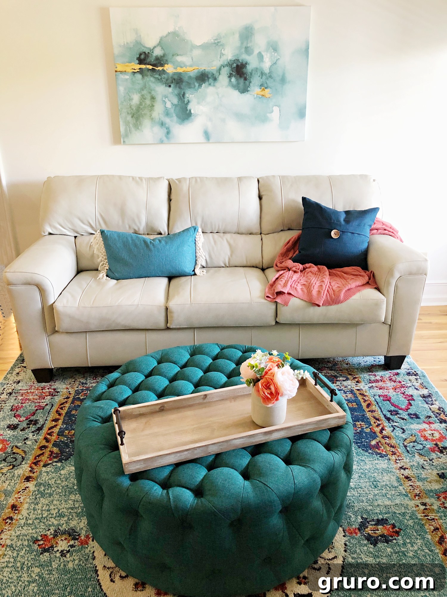 Teal living room with captivating abstract art, a comfortable ottoman, and a patterned rug creating a cozy lake condo ambiance.