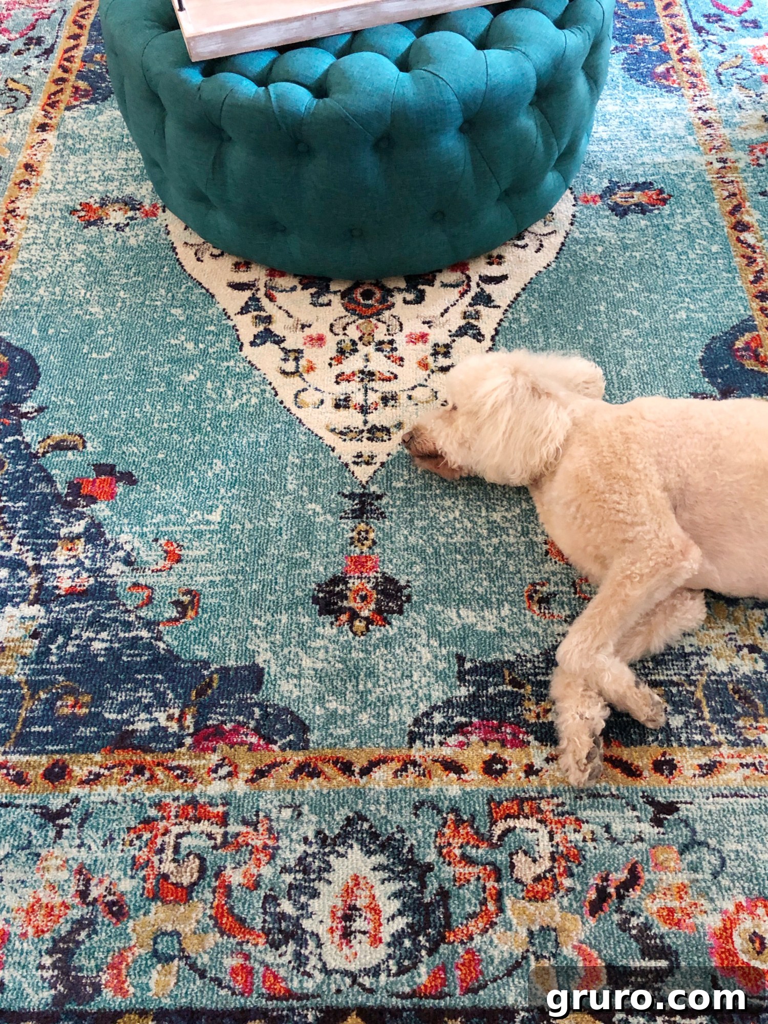 Close-up of a stylish teal rug and a plush ottoman, highlighting key accents in a comfortable coastal living room.