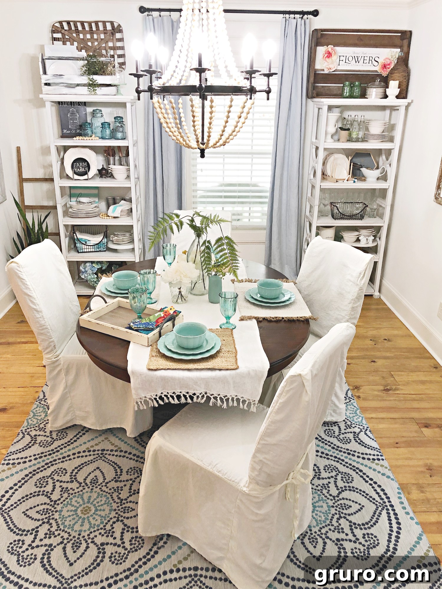 A beautifully set vintage farmhouse dining table with comfortable slipcovered chairs, adorned with charming dinnerware and a centerpiece, creating an inviting atmosphere.