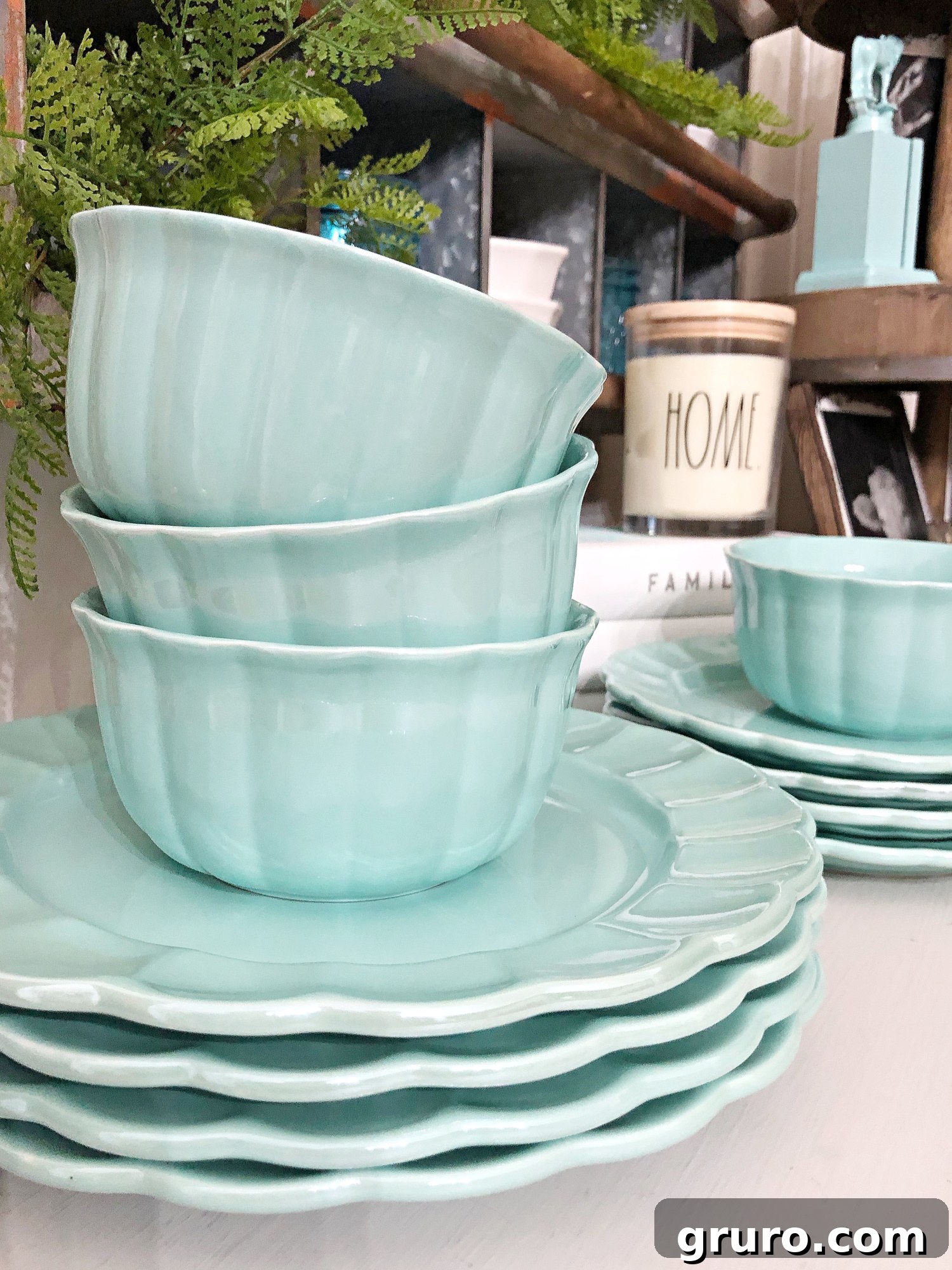 Close-up of a stack of beautiful Pioneer Woman dinner plates in a captivating teal hue, highlighting their unique luster and vintage-inspired design, ready to grace a farmhouse table.