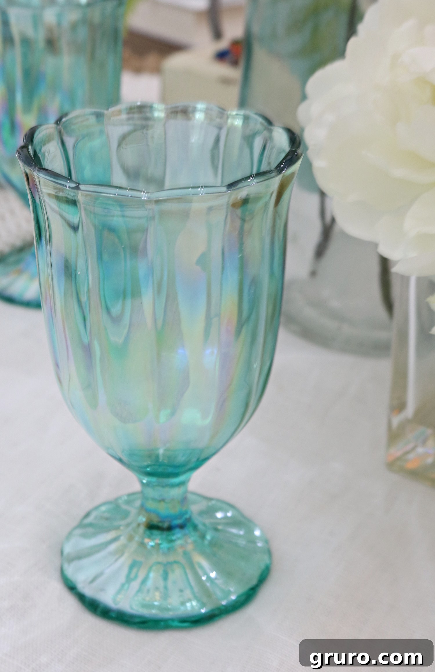 A close-up shot of a single, elegantly designed teal glass, showcasing its captivating pearlized luster and sophisticated appeal, perfectly suited for a vintage farmhouse table setting.