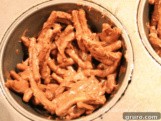 Shaping chocolate peanut butter chow mein mixture into a nest in a muffin tin