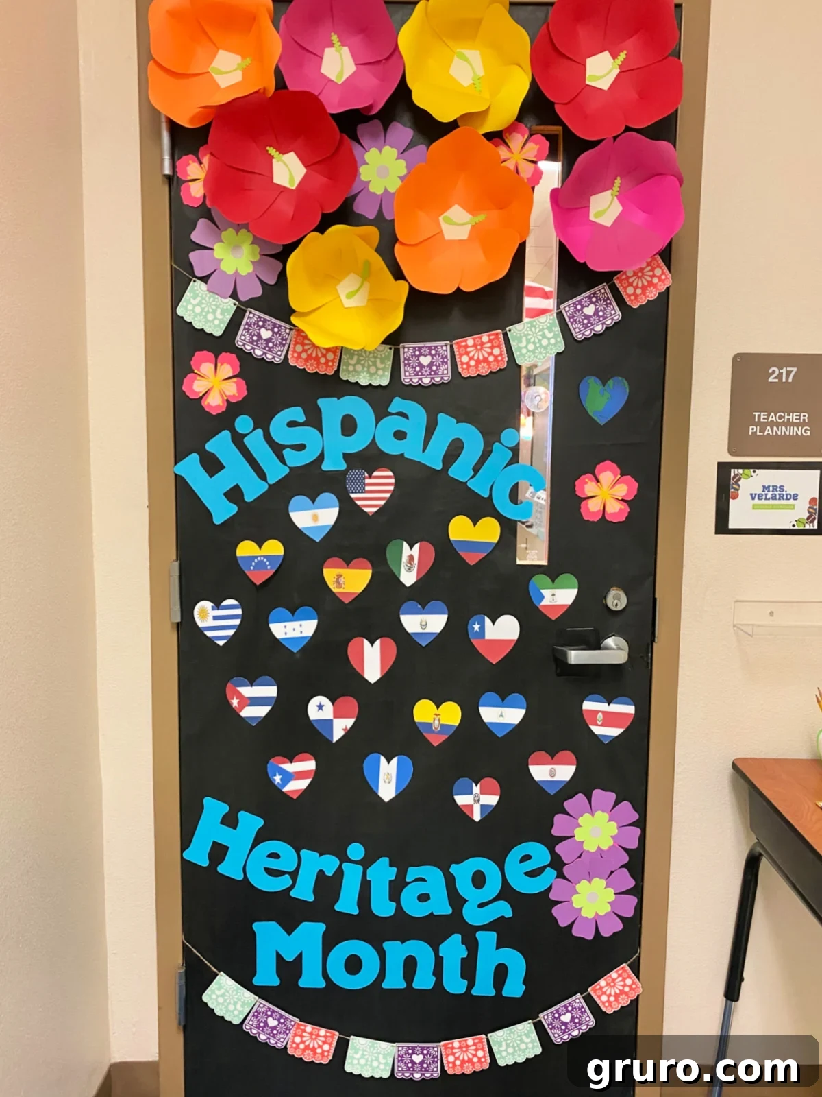 Hispanic Heritage Month Door Decor Ideas 2 Black classroom door with the words 'Hispanic Heritage Month' with hibiscus flowers and hearts of country flags.