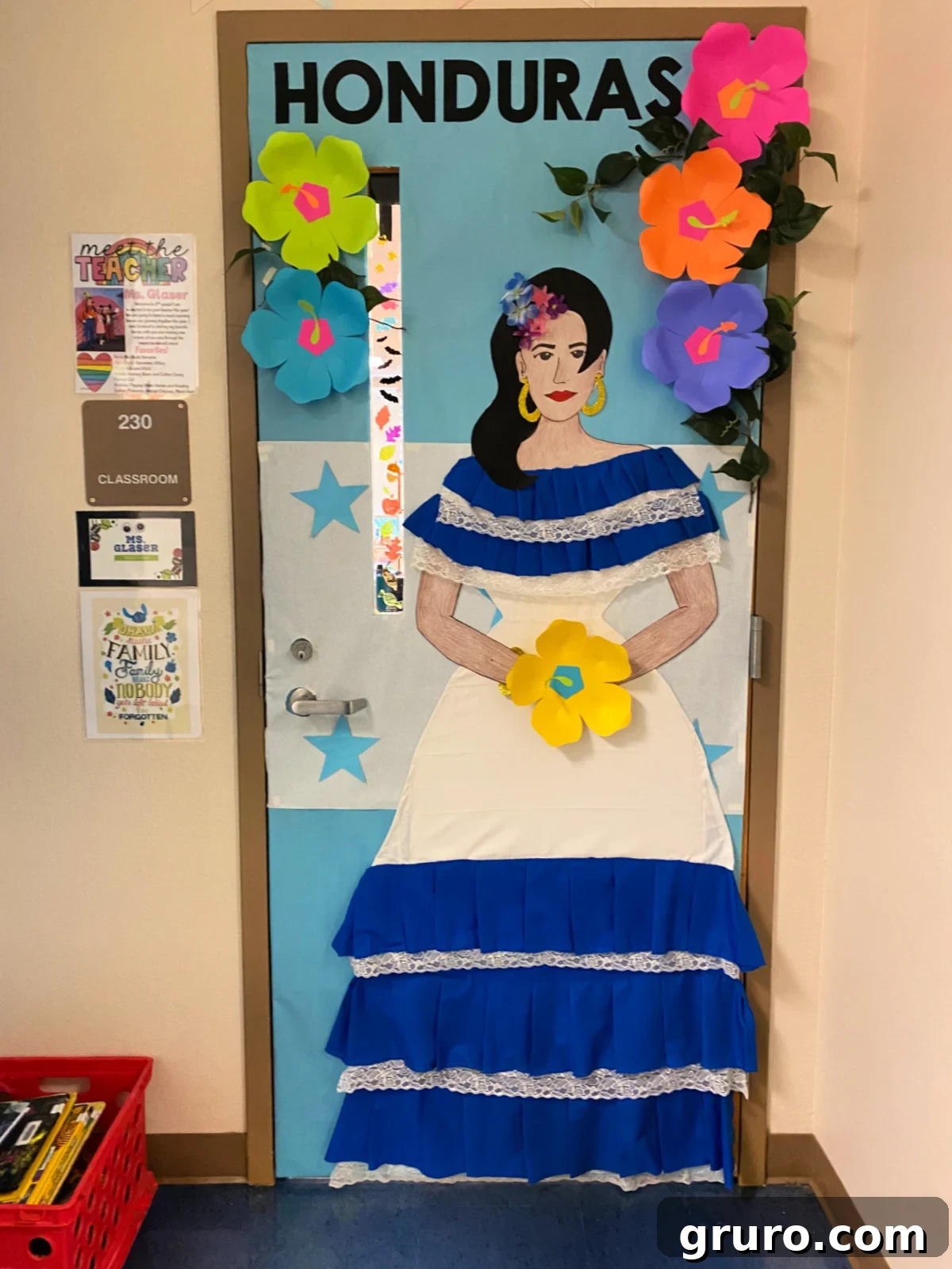 Hispanic Heritage Month Door Decor Ideas 15 Classroom door with a female in a white and blue dress with the Honduras flag and tropical hibiscus flowers.